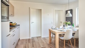A modern kitchen with a wooden dining table set for four, a built-in oven, and a hanging pendant light. - Smart Resorts - Haus Saphir - Ferienwohnung 506 mit 2 Schlafzimmern, max (Winterberg)
