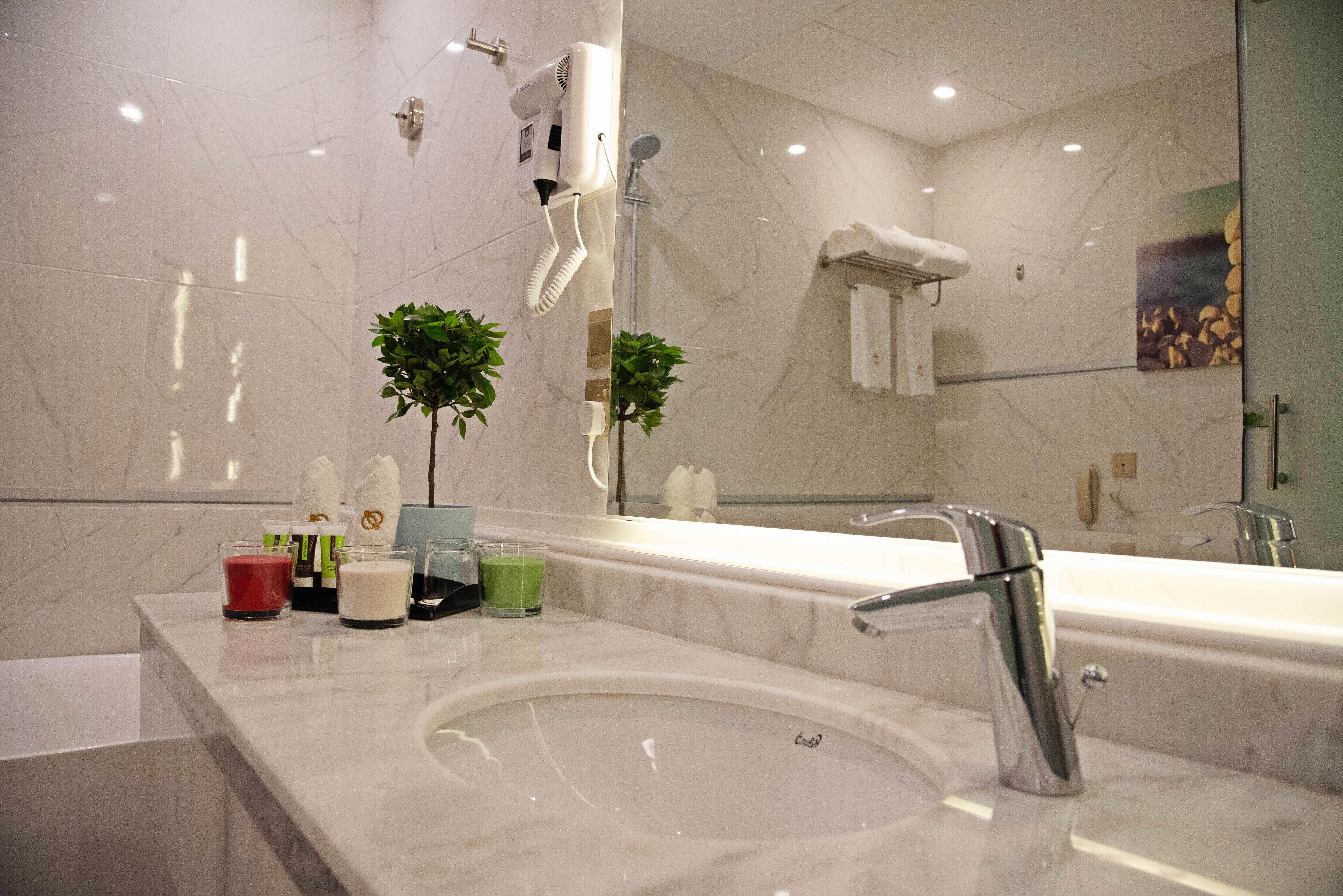 A modern bathroom with a large mirror, a sink, a hairdryer, and a shower.