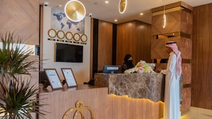 Een houten receptiebalie in een hotel, met een wereldkaart, klokken en een scherm.