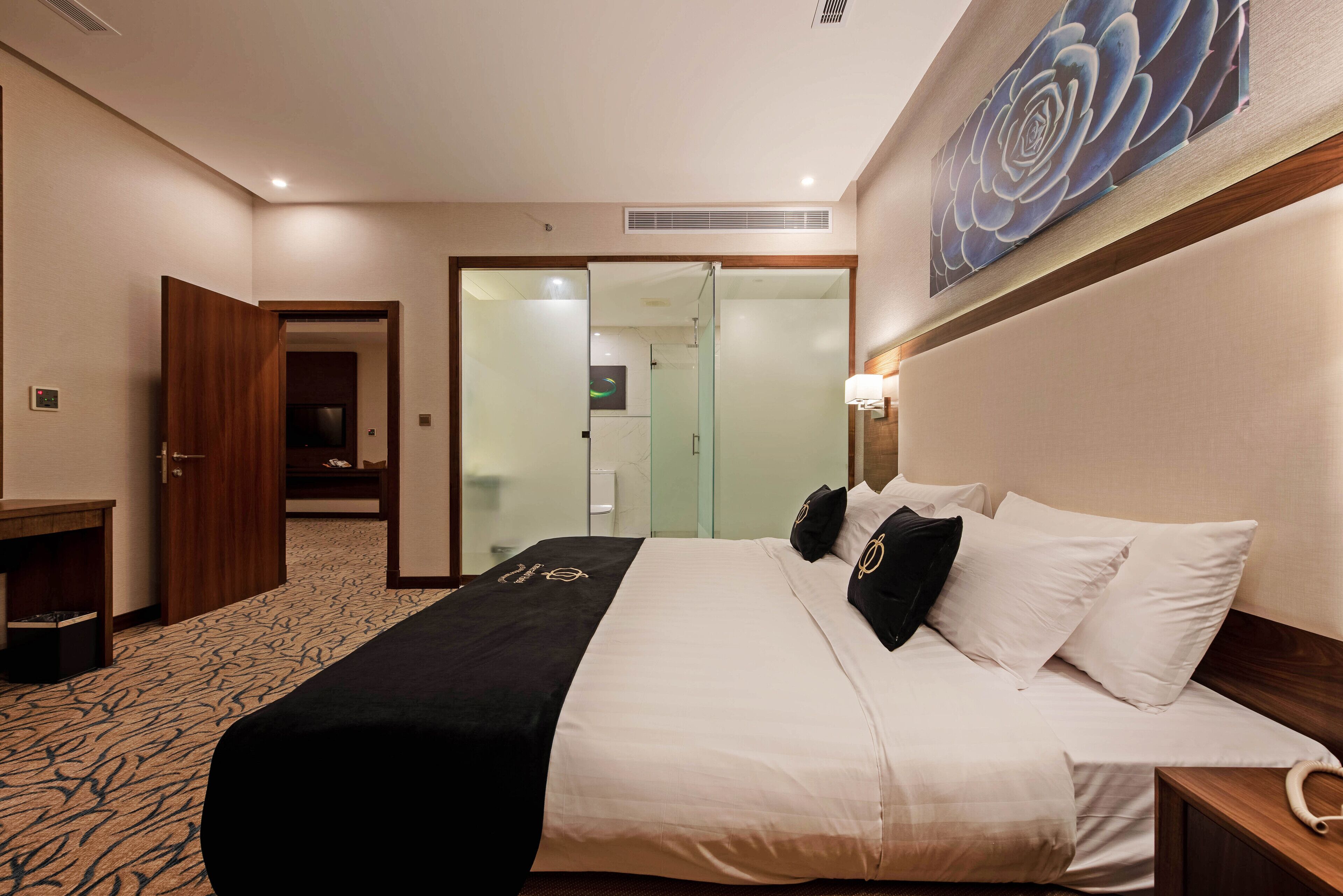 Una habitación de hotel con cama, escritorio, puerta y separador de vidrio.