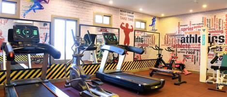 A gym with treadmills, ellipticals, and a wall with motivational sports-related words and phrases.