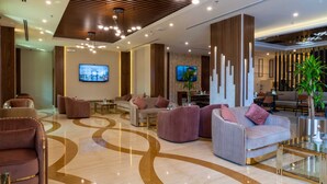 Een moderne lobby met comfortabele zithoeken, een grote televisie en een decoratieve kolom.