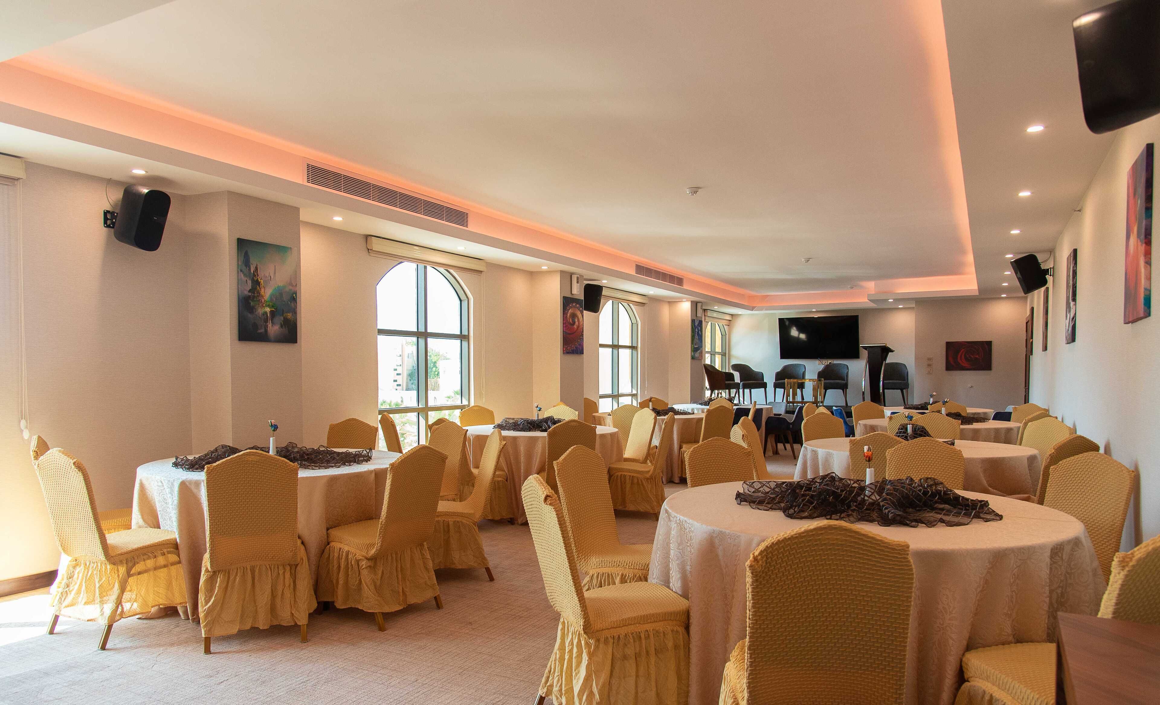 A conference room with round tables and chairs, large windows, and a flat-screen TV.