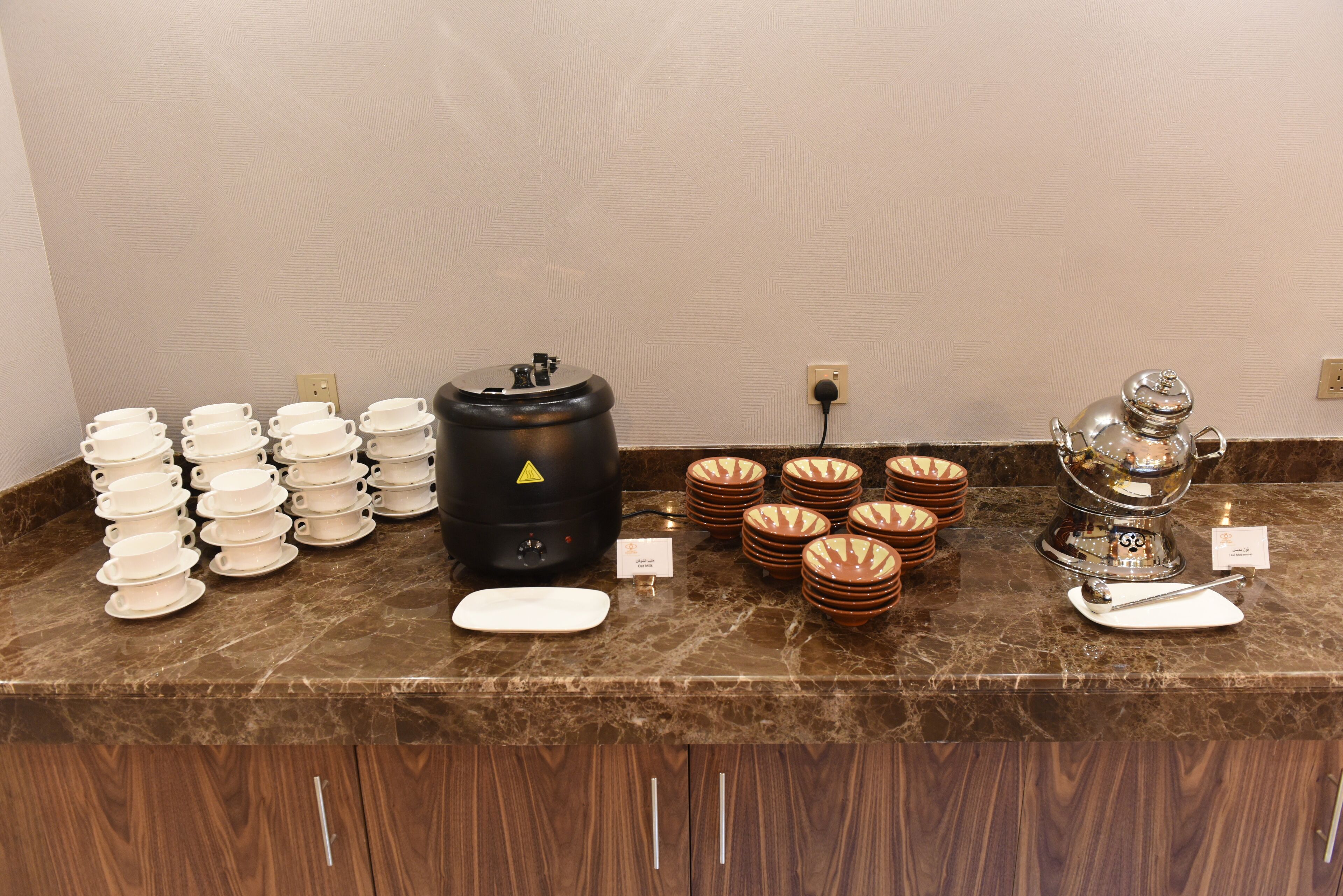 Ein reichhaltiges Buffet mit verschiedenen Servierstationen, darunter eine Kaffeestation mit einem großen schwarzen Behälter und eine Tee-Station mit einem silbernen Spender.