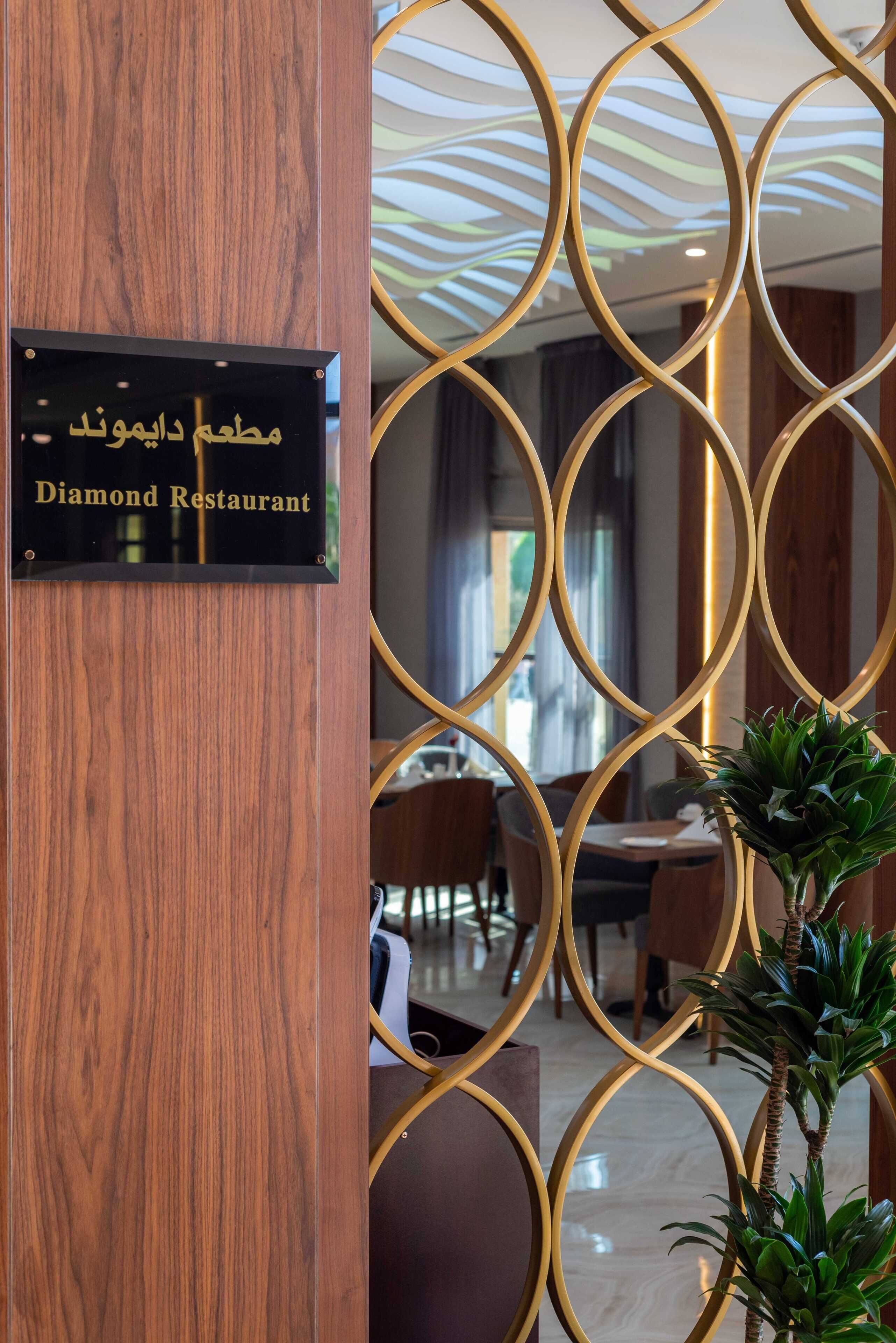 A sign for the Diamond Restaurant with a modern interior design, including a wooden partition and a geometric ceiling pattern.