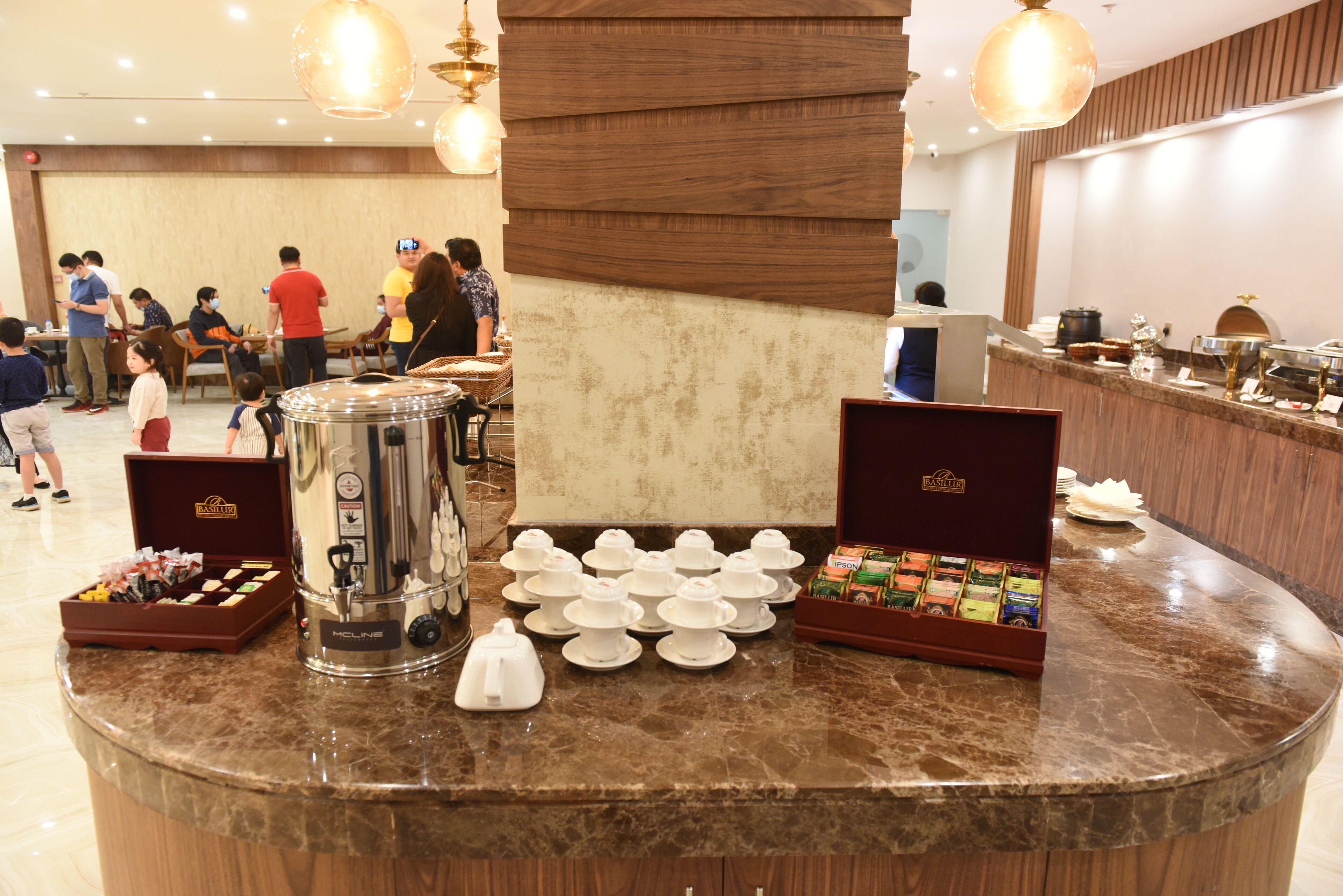 A buffet area with a coffee machine, tea pots, and a variety of food items.