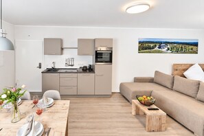 A modern kitchen with a built-in oven and a dining area with a wooden table set for two. - "Relaxation and Adventure Await at Smart Resorts Haus Azur!" (Winterberg)