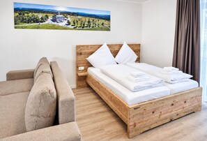 A bedroom with a wooden bed, a wooden headboard, a single bed with white linens, a brown sofa, and a painting of a landscape on the wall. - "Relaxation and Adventure Await at Smart Resorts Haus Azur!" (Winterberg)