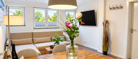 Ein modernes Wohnzimmer mit Holzesstisch, Sofa und einer großen Pendelleuchte.