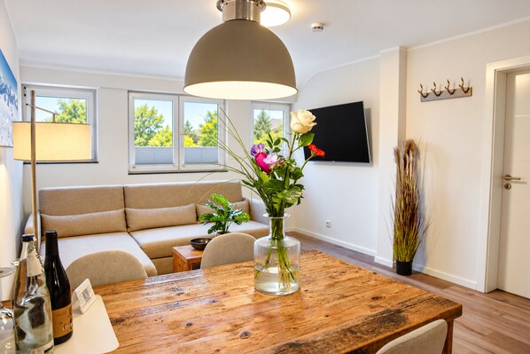 A modern living room with a wooden dining table, sofa, and a large ceiling light fixture.