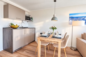 A modern kitchen with a dining area, wooden flooring, and a view of a snowy landscape.