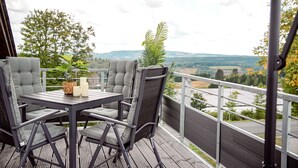 Ein überdachter Außenbereich mit Tisch und Stühlen, mit Blick auf eine malerische Landschaft.