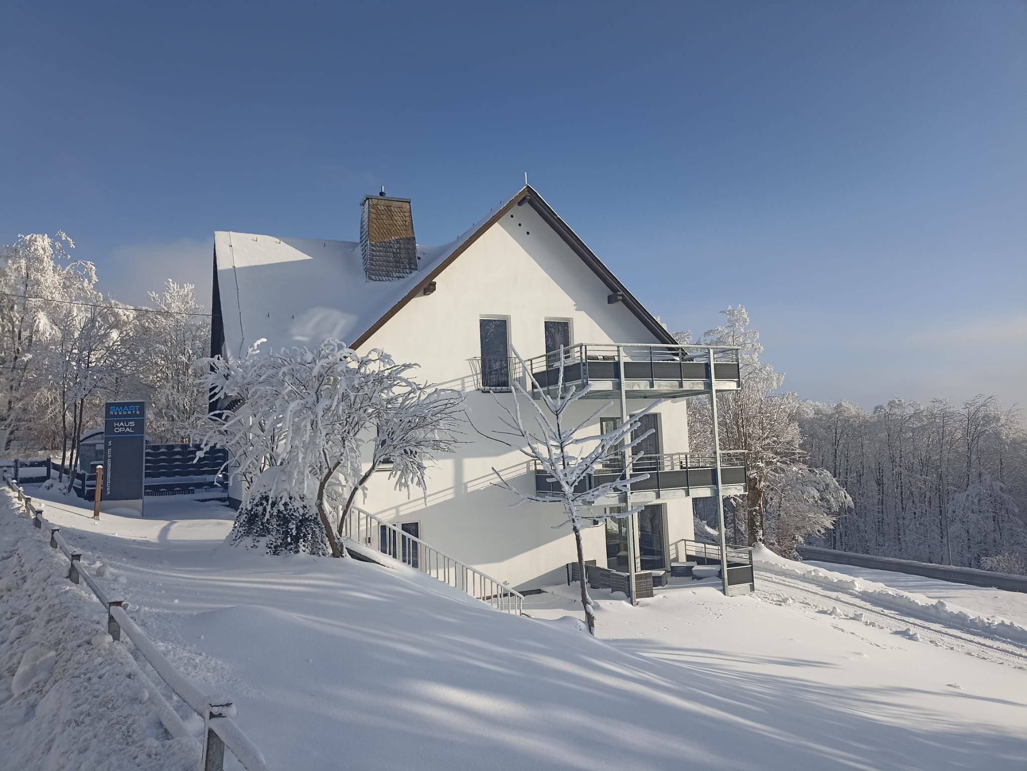 Un edificio cubierto de nieve con un balcón y un cartel que indica que es un resort inteligente.