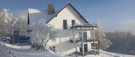 Un edificio cubierto de nieve con un balcón y un cartel que indica que es un resort inteligente.