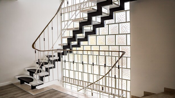 Un escalier moderne au design géométrique, composé d’une combinaison de marches noires et blanches et agrémenté d’un mur en panneaux de verre.