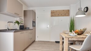 A modern kitchen with a central island, a dining table with chairs, and a wooden ceiling. - Smart Resorts - Haus Azur - Ferienwohnung 808, Max. 4 Personen (Winterberg)