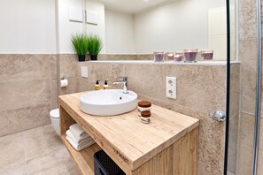 Une salle de bain moderne avec un lavabo rond, un meuble-lavabo en bois et une cabine de douche en verre.