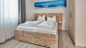 A neatly made bed with white linens and pillows, a wooden headboard, and a painting of a snowy mountain landscape on the wall. - Smart Resorts - Haus Azur - Ferienwohnung 808, Max. 4 Personen (Winterberg)
