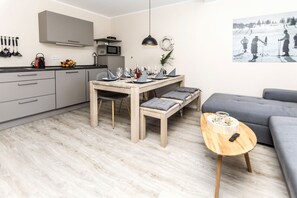 Eine moderne Küche mit grauen Schränken, einem Holzespeisetisch und einem grauen Sofa.