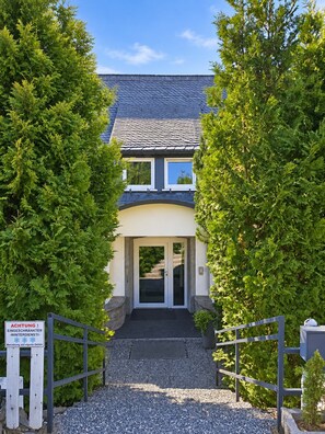 A building with a dark roof, a white door, and a gravel pathway leading to the entrance.