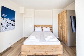 A room with a bed, a wooden headboard, a door, a wooden wardrobe, and a framed picture on the wall. - Smart Resorts - Haus Diamant - Ferienwohnung 706 mit Balkon, Max. 6 Personen (Winterberg)