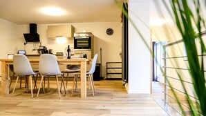 A modern kitchen with wooden flooring, a dining table with four chairs, and a built-in oven.