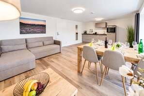 Um espaço de estar moderno com sofá, mesa de jantar, cadeiras e uma fruteira.
