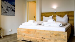 A wooden bed with white linens and pillows, a wooden headboard, and a night light.