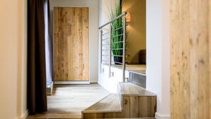 A wooden staircase with a metal handrail leading to a landing.