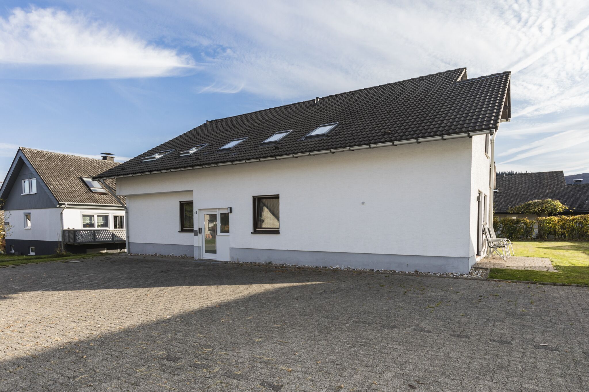 A single-story building with a tiled roof, a small front porch, and a paved driveway.
