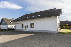 Un bâtiment d’un seul étage, doté d’un toit en tuiles, d’un petit porche à l’avant et d’une allée pavée.