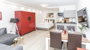 Ein modernes Hotelzimmer mit einem Bett, einem Essbereich, einer Küchenzeile und einem roten Wandschrank.