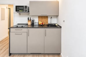 A compact kitchen with a microwave, a sink, and a fruit bowl on the countertop.