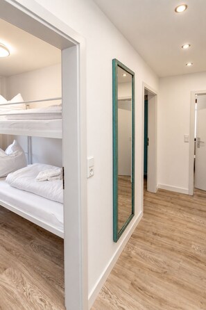 A room with bunk beds, a large mirror, and a wooden floor.