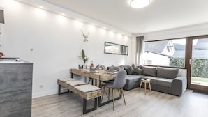 A modern living room with a dining area, a grey sofa, and a wooden dining table. - "Charming Getaway in Winterberg: Your Perfect Family Retreat Awaits!" (Winterberg)