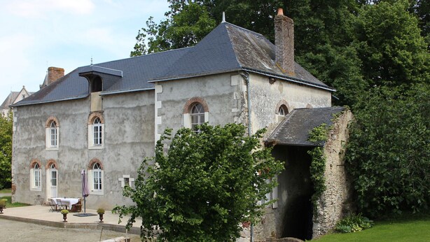 A large, historic stone building with multiple arched windows and a covered entrance.