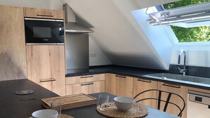 A modern kitchen with wooden cabinets, a Bosch microwave, a built-in oven, and a skylight.