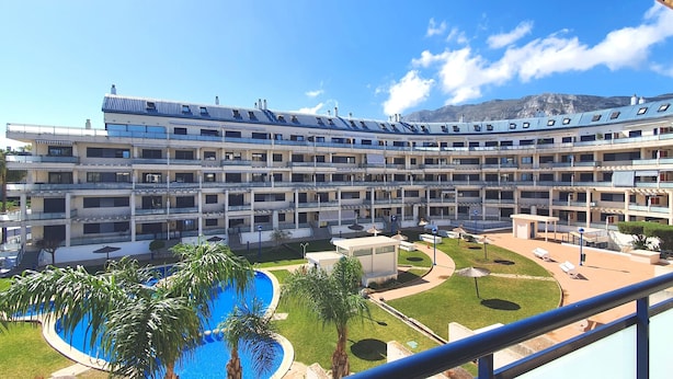 Un hôtel à plusieurs étages doté d’une cour intérieure, d’une piscine et offrant une vue sur les montagnes.