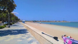 Une plage avec une promenade dallée, un kayak et une planche de paddle.