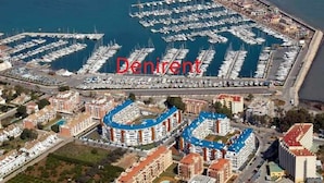 Une vue aérienne d’une marina où sont amarrés de nombreux bateaux, entourée de bâtiments résidentiels et d’un grand hôtel dont le toit bleu est facilement reconnaissable.