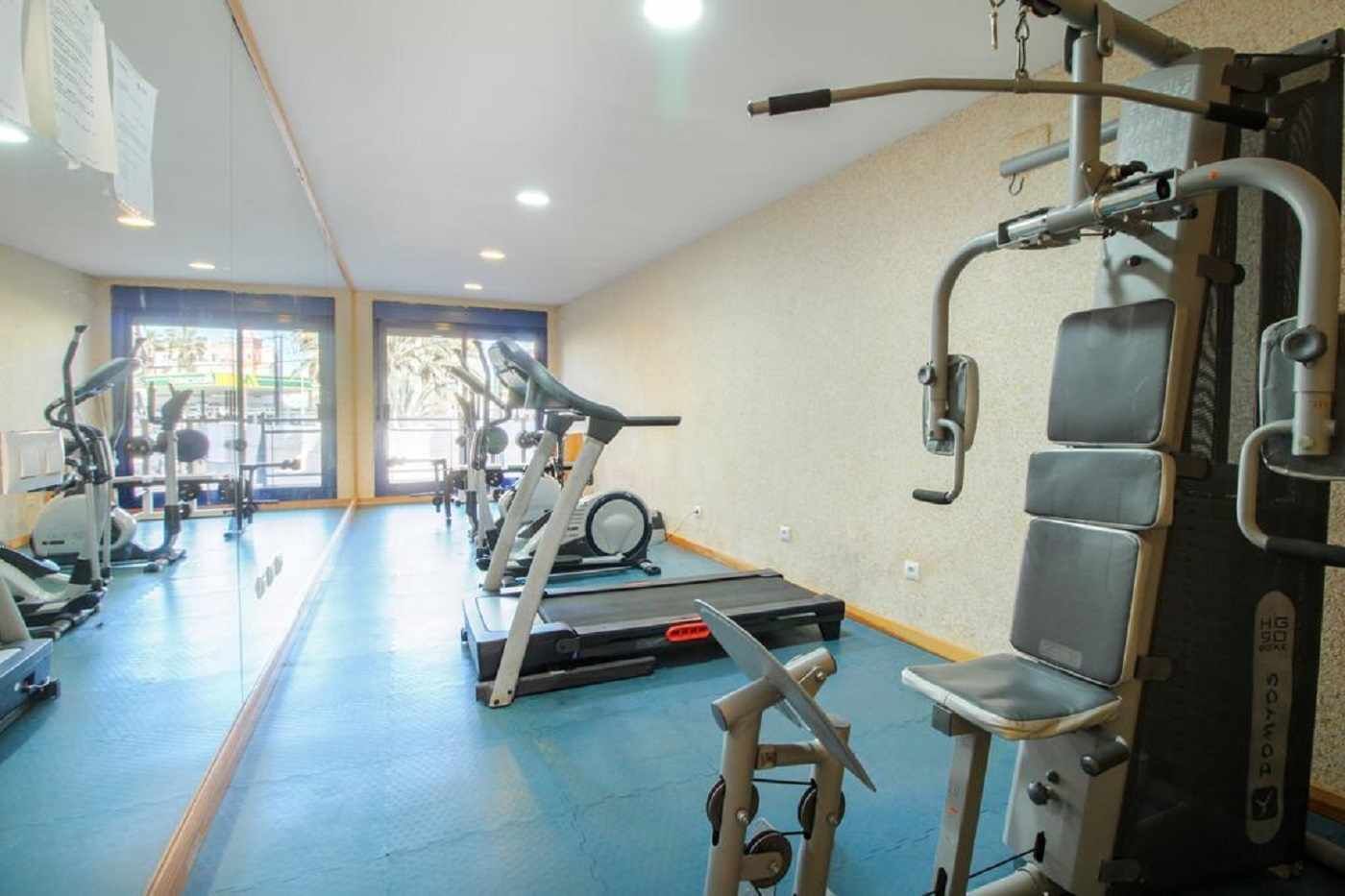 A gym with cardio machines, weight training equipment, and a blue floor.
