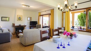 Un coin repas avec une table dressée pour quatre personnes, une cheminée et un téléviseur en arrière-plan.