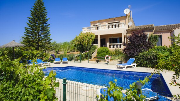 Un espace piscine comprenant des chaises longues, une piscine et un bâtiment doté d’un balcon.