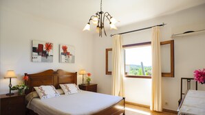 Une chambre bien éclairée, avec un lit en bois, des lampes de chevet et des œuvres d’art accrochées aux murs.