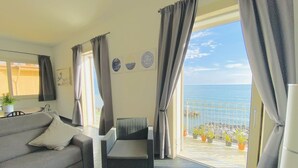 Un balcon avec vue sur la mer, un canapé, un fauteuil et des plantes en pot.