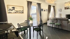 Un salon comprenant une table à manger, des chaises, un canapé, un téléviseur et une vue sur la mer.