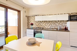 Une cuisine moderne avec des meubles blancs, un pare-feu en carreaux et un coin repas comprenant une table blanche et deux chaises.