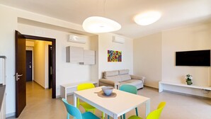 Een moderne woonkamer met een witte tafel, kleurrijke stoelen, een bank en een televisie.