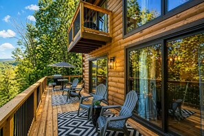 A wooden deck with Adirondack chairs, a grill, and a glass door leading to a deck area. - Tri-Level Log Cabin Massanutten Resort Hot Tub Seasonal Community Pool Firepit (McGaheysville)