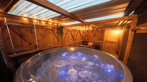 A hot tub in a wooden room with a sloped ceiling and wooden walls.
